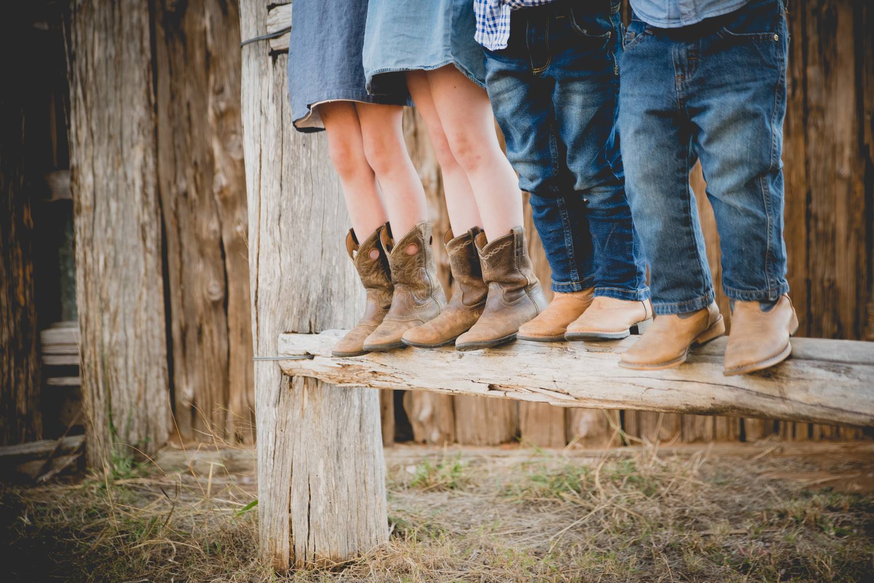 Kids in cowboy boots standing on wooden fence